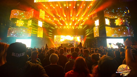 Das SonneMondSterne-Festival: Feiernde Menschen stehen vor einer großen hell erleuchteten Bühne